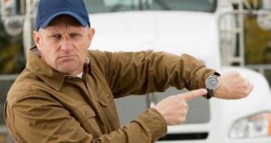 Uomo che indica l’orologio con espressione tesa, simbolo di stress da confronto e pressione temporale